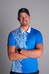 Man wearing a blue shirt with a patterned tie and black cap against a gray background